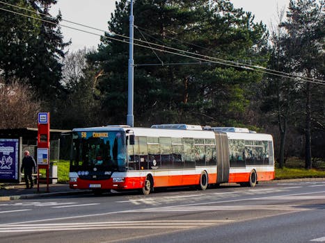 pexels-photo-30487300-30487300 Articulated bus at a Prague bus stop during daytime with trees in the background.